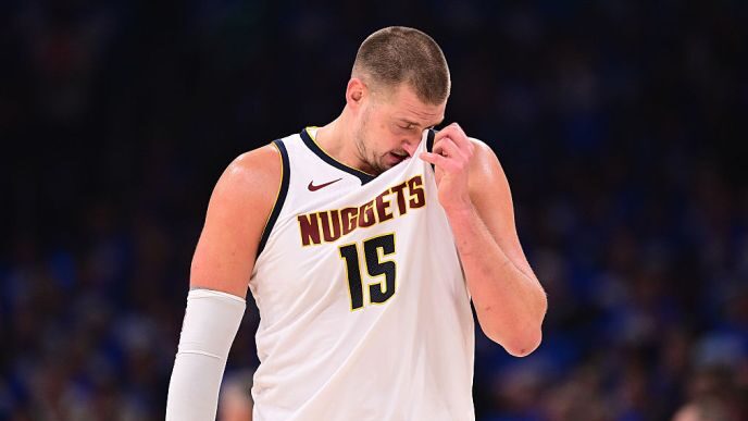 Nikola Jokić, visiblement déçu, en maillot des Nuggets, tête baissée lors d’un match sous haute pression.
